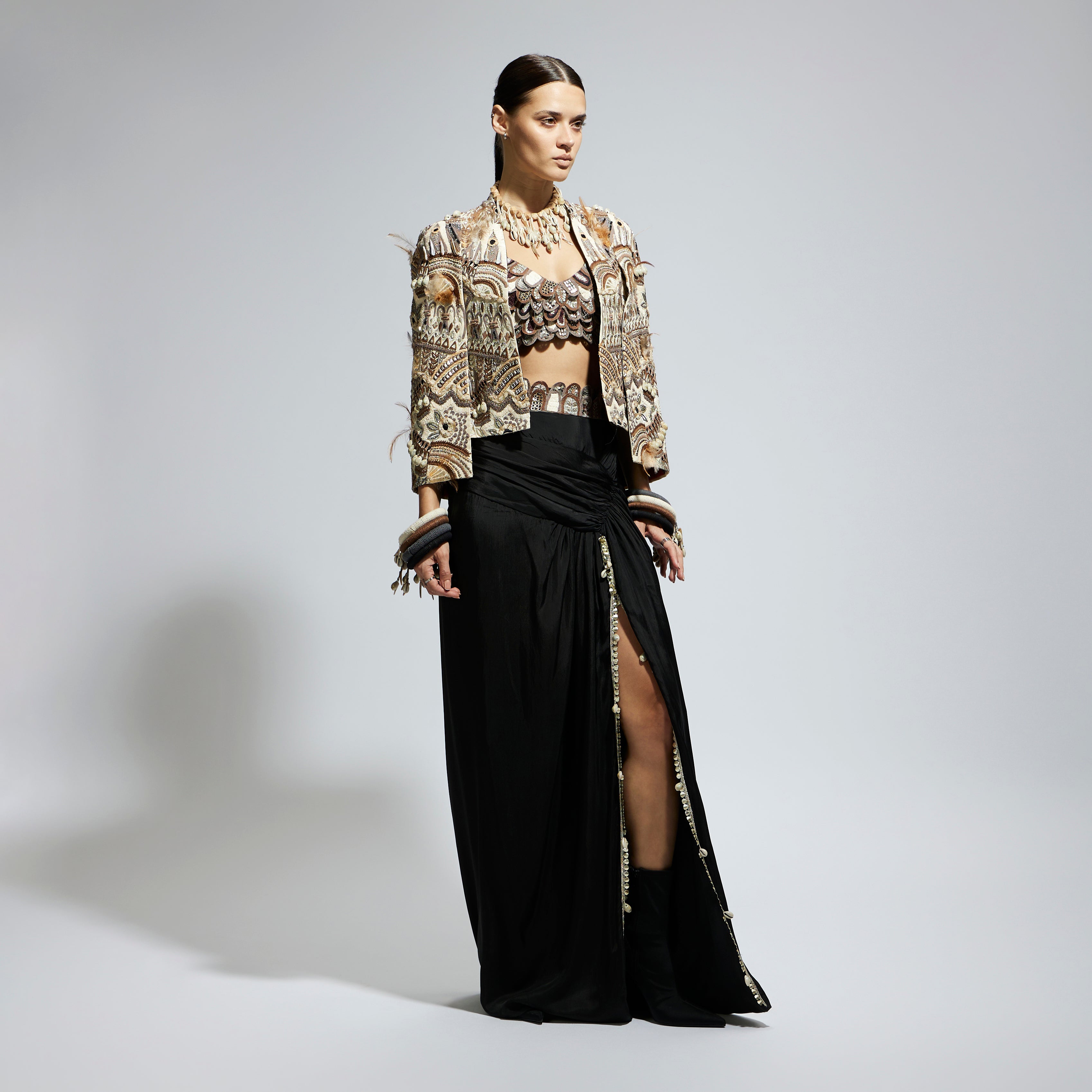 SAMSARA: IVORY ABSTRACT FEATHER CAPE JACKET PAIRED WITH 3D SCALLOP BUSTIER AND BLACK HIGH SLIT SKIRT