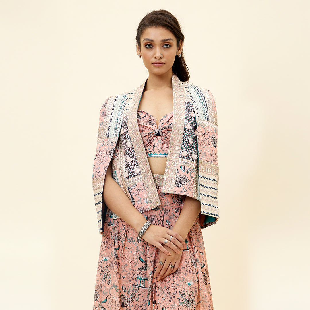 PINK MOR JAAL PRINT BIKINI BUSTIER TEAMED WITH BOX PLEATED PANTS AND A PATCHWORK NOOR CAPE JACKET