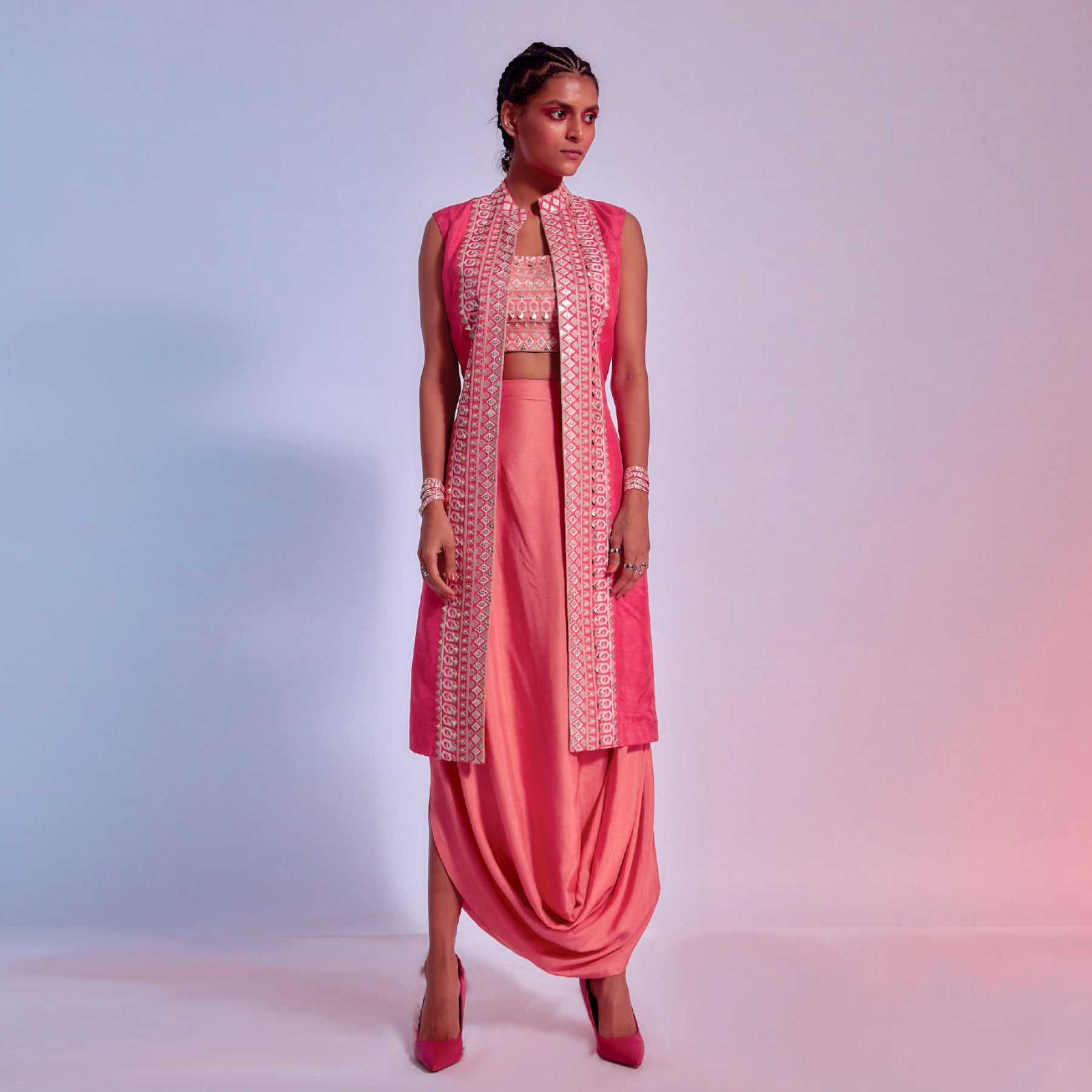 EMBELLISHED CORAL BUSTIER TEAMED WITH A SLEEVELESS JACKET AND A DRAPED SKIRT