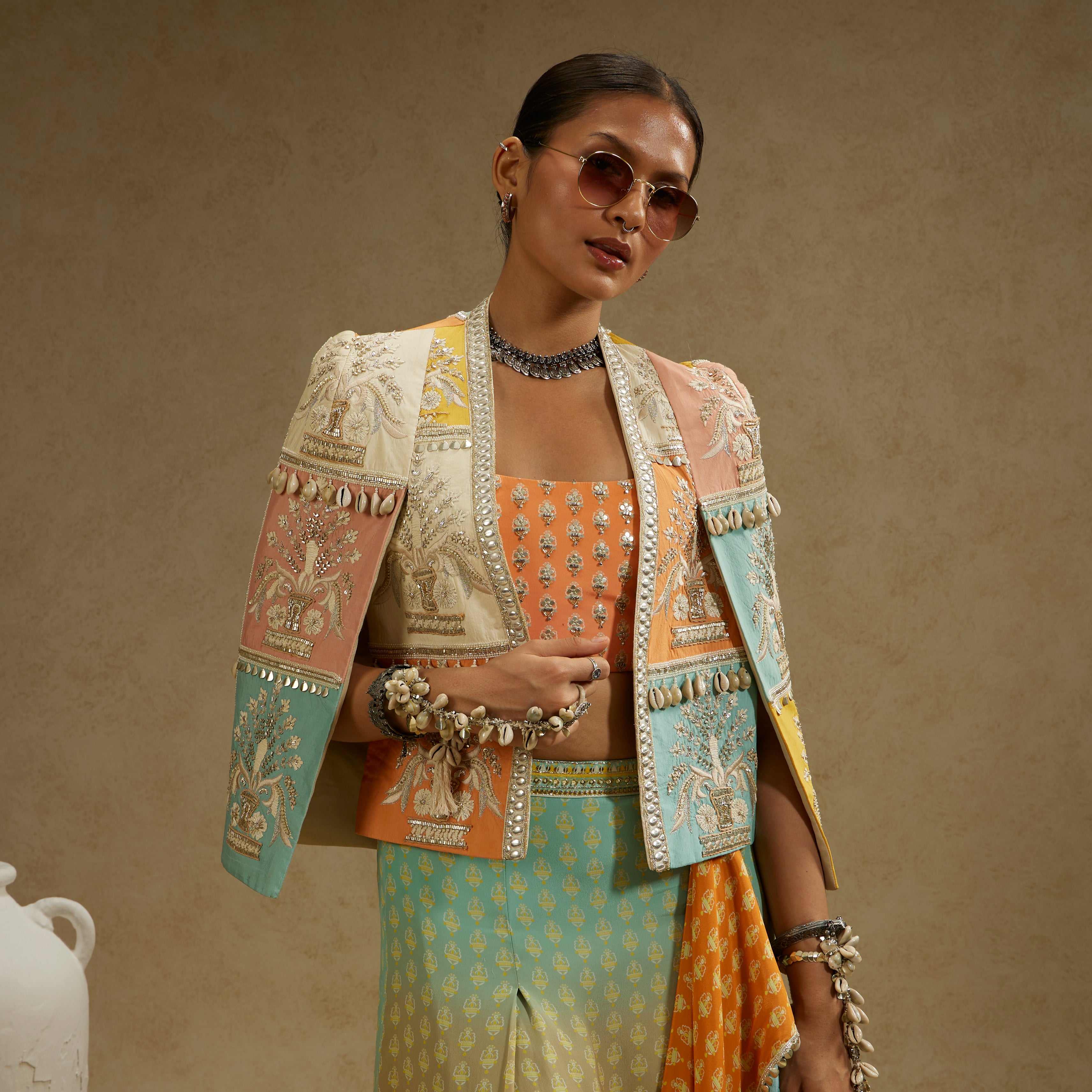 COLOUR BLOCKED PATCHWORK CAPE JACKET PAIRED WITH AN EMBELLISHED BUSTIER AND AN OMBRE PRINTED DRAPED SKIRT