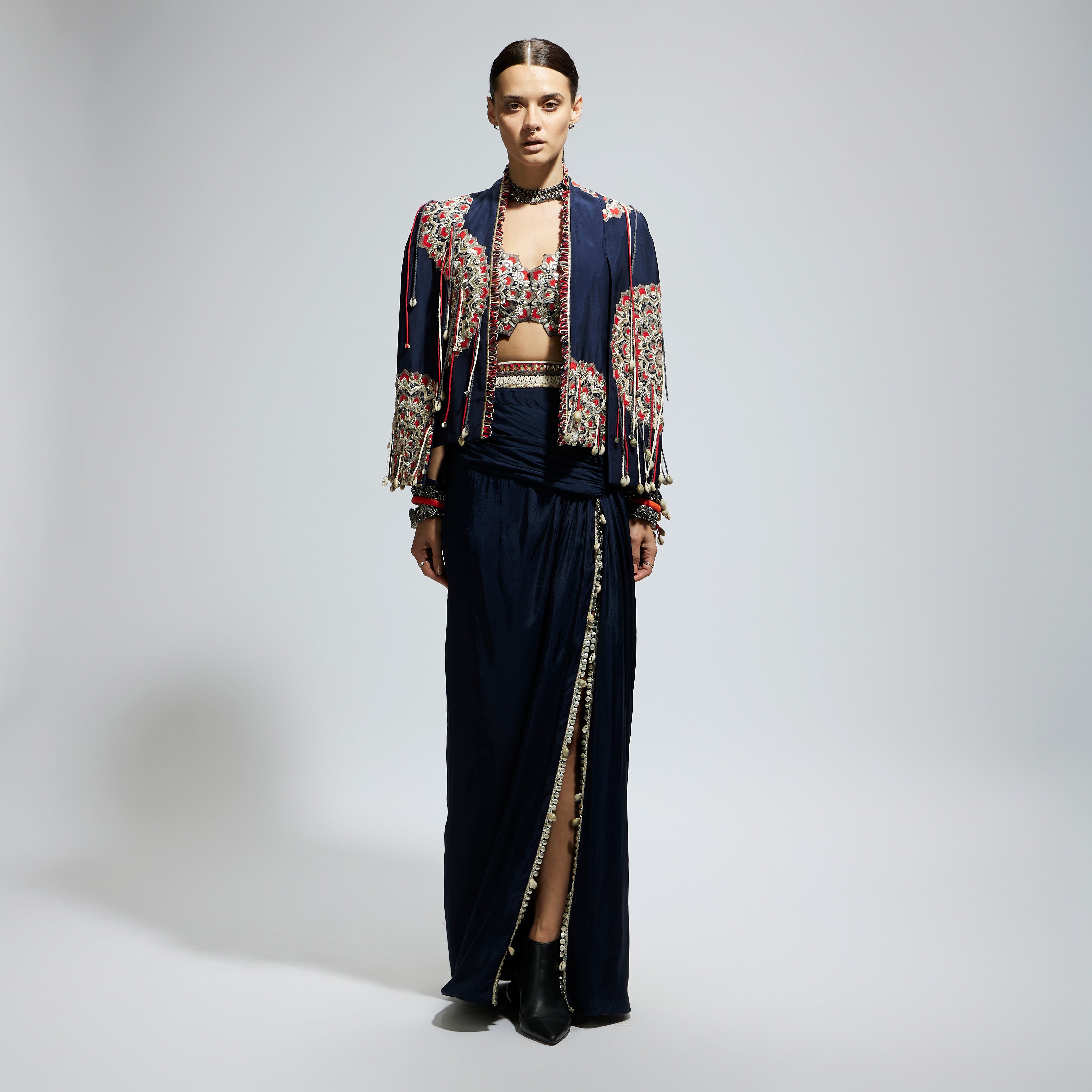 SAMSARA: BLUE ASYMETRIC THREADWORK CAPE JACKET PAIRED WITH AN EMBELLISHED BUSTIER AND HIGH SLIT SKIRT