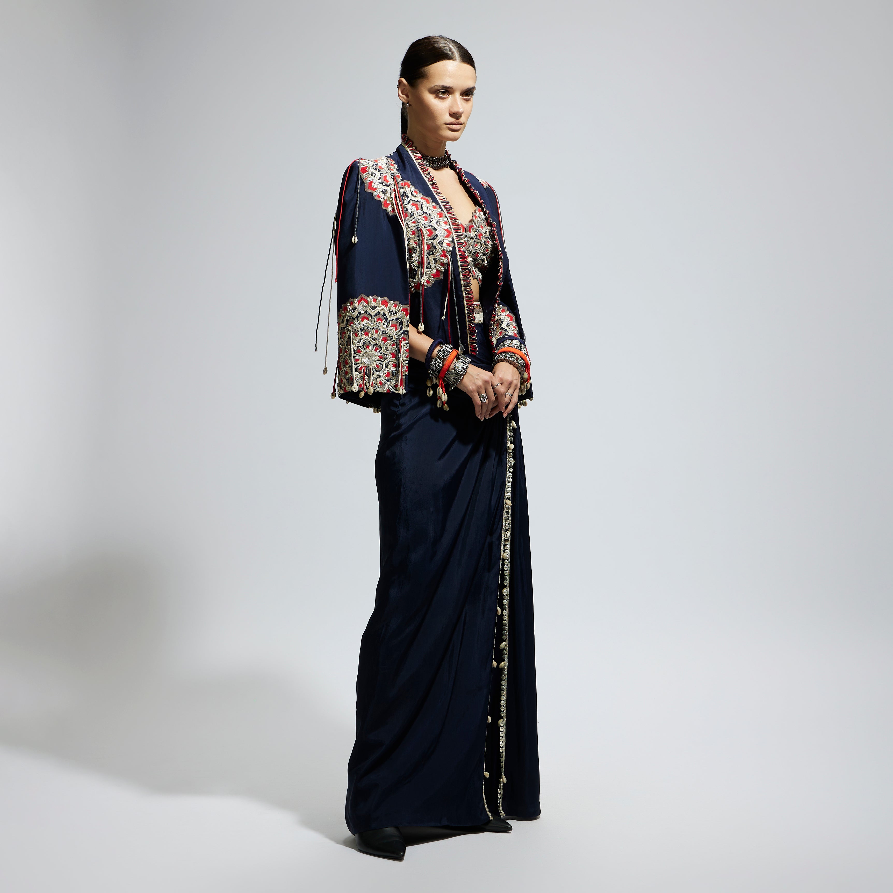 SAMSARA: BLUE ASYMETRIC THREADWORK CAPE JACKET PAIRED WITH AN EMBELLISHED BUSTIER AND HIGH SLIT SKIRT