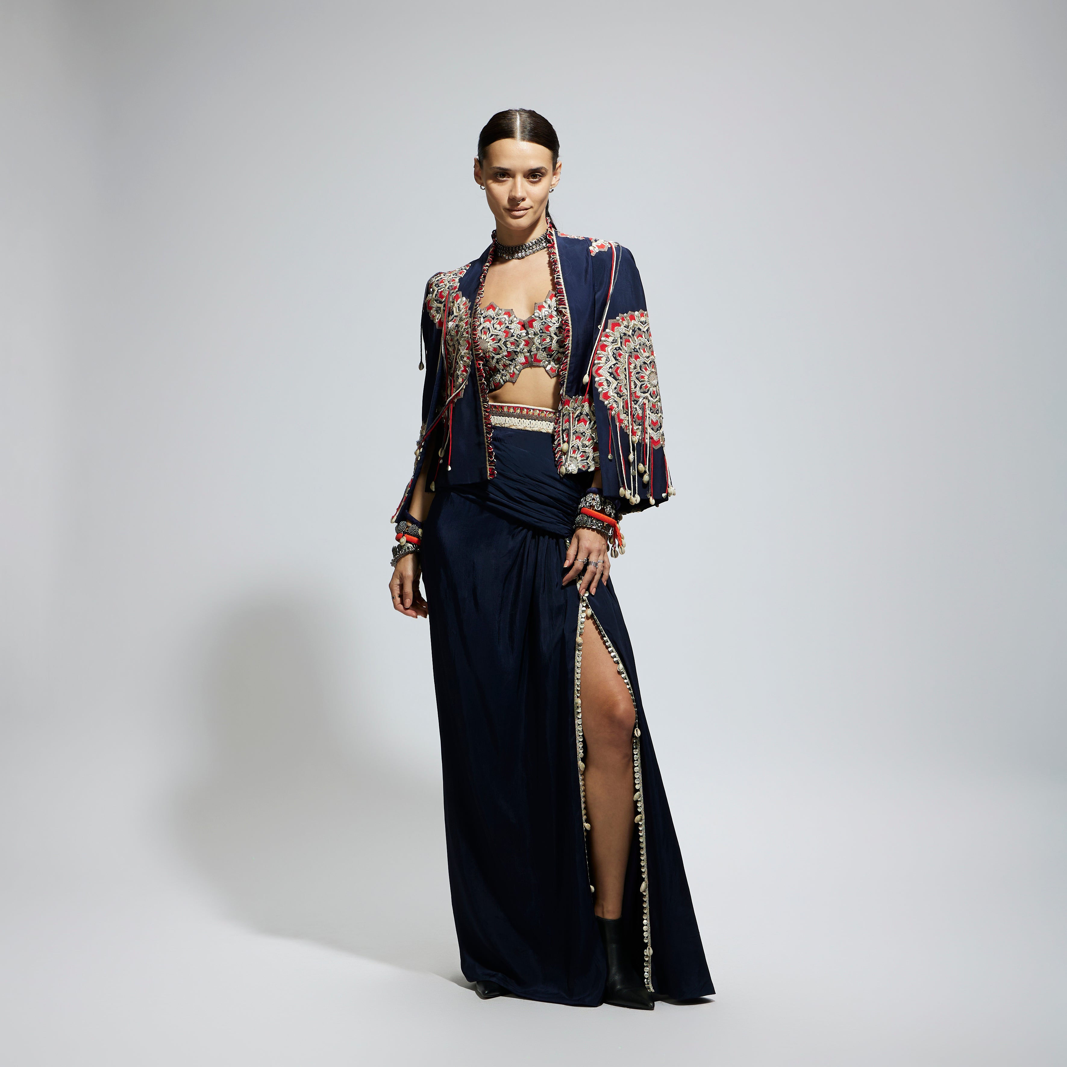 SAMSARA: BLUE ASYMETRIC THREADWORK CAPE JACKET PAIRED WITH AN EMBELLISHED BUSTIER AND HIGH SLIT SKIRT