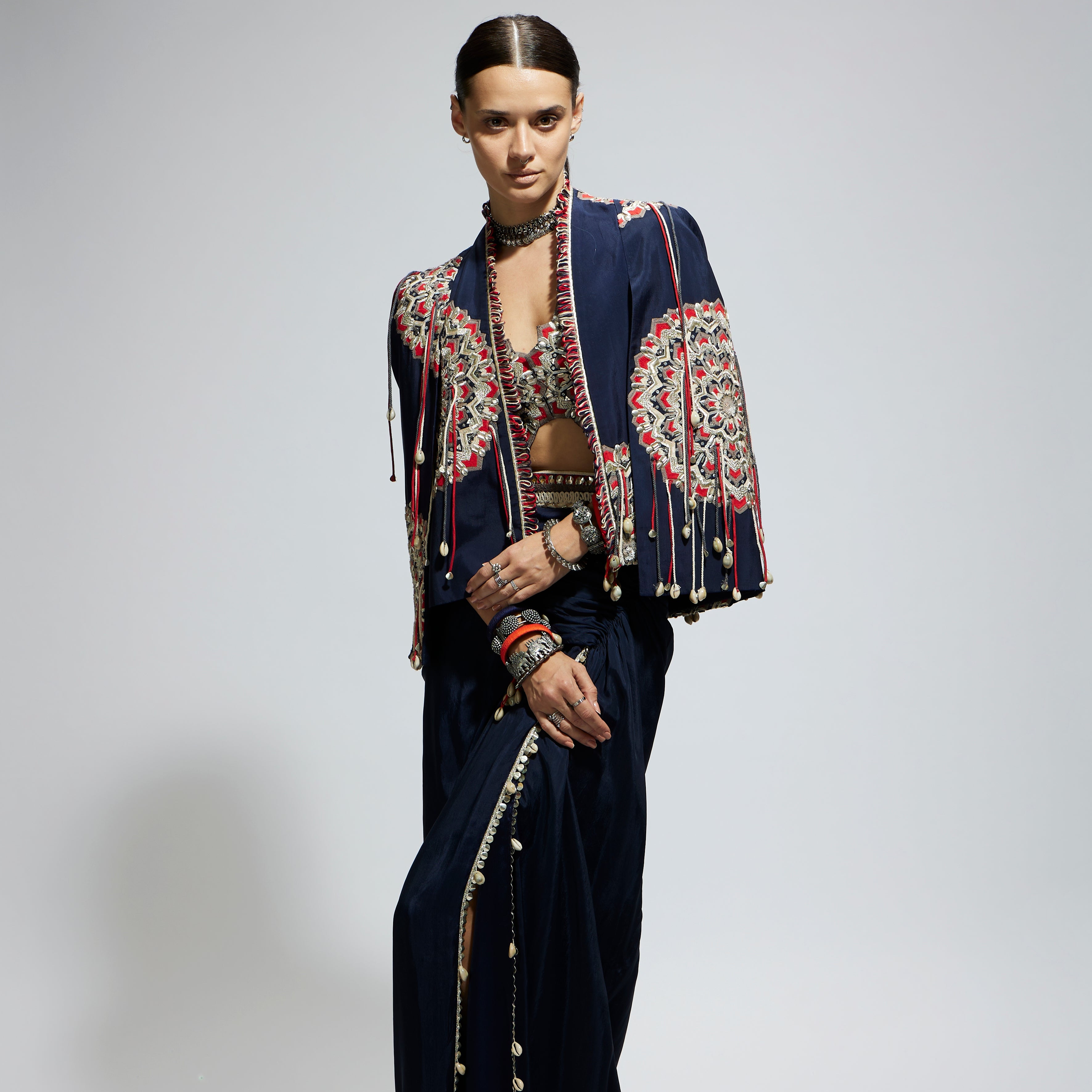 SAMSARA: BLUE ASYMETRIC THREADWORK CAPE JACKET PAIRED WITH AN EMBELLISHED BUSTIER AND HIGH SLIT SKIRT