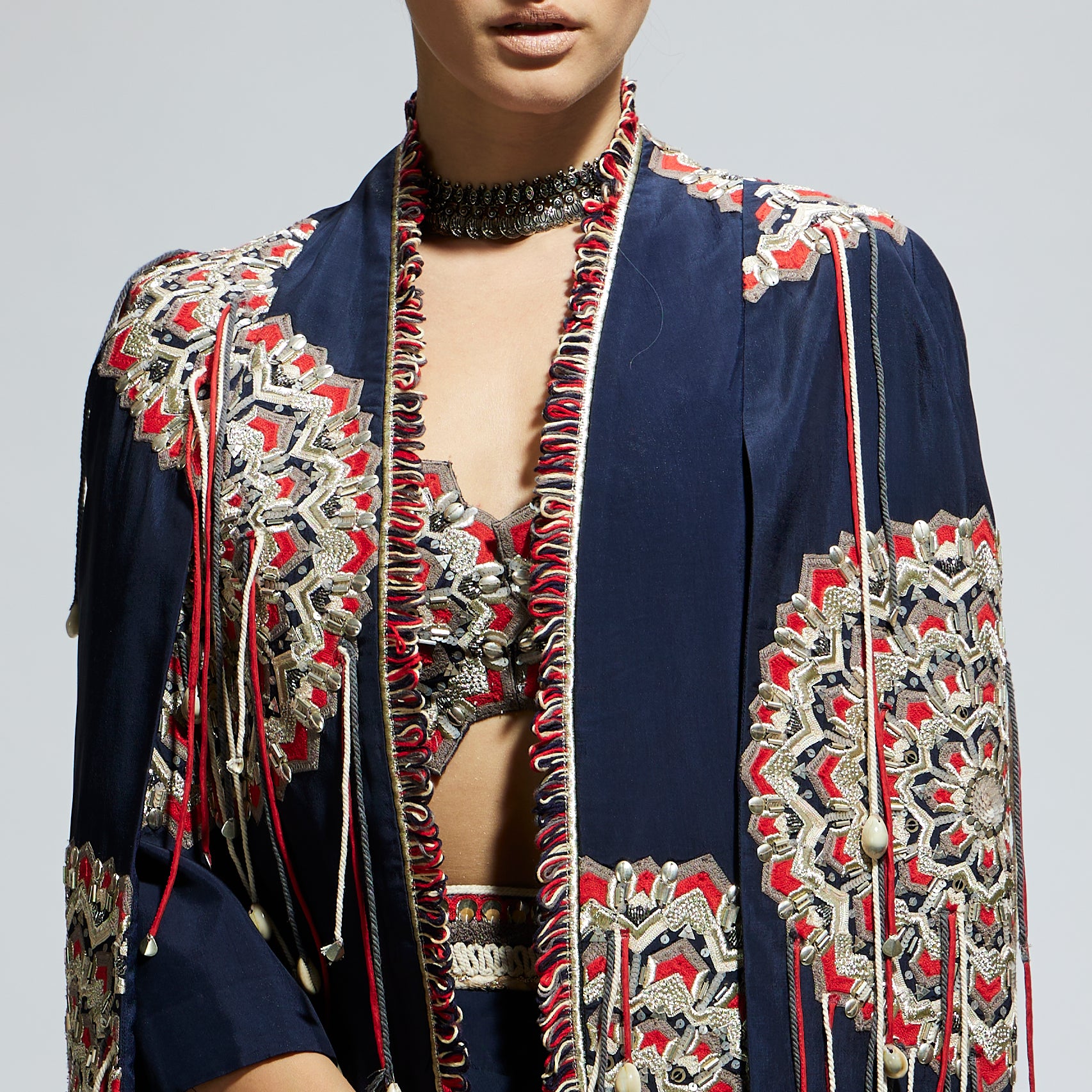 BLUE ASYMETRIC THREADWORK CAPE JACKET PAIRED WITH AN EMBELLISHED BUSTIER AND HIGH SLIT SKIRT