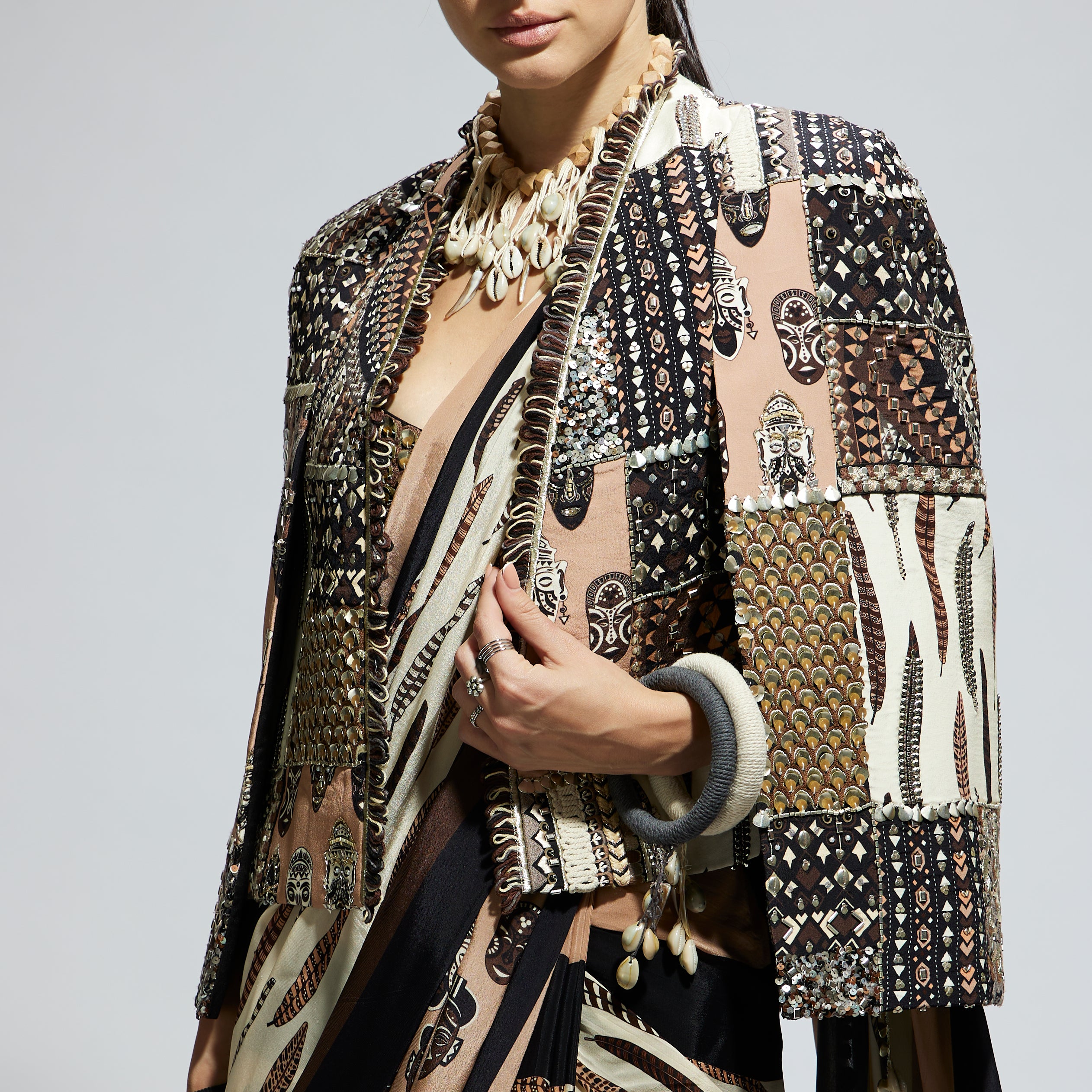 MASK AND FEATHER PRINT CASCADE SAREE PAIRED WITH METALLIC SCALLOP BUSTIER WITH PATCHWORK CAPE JACKET