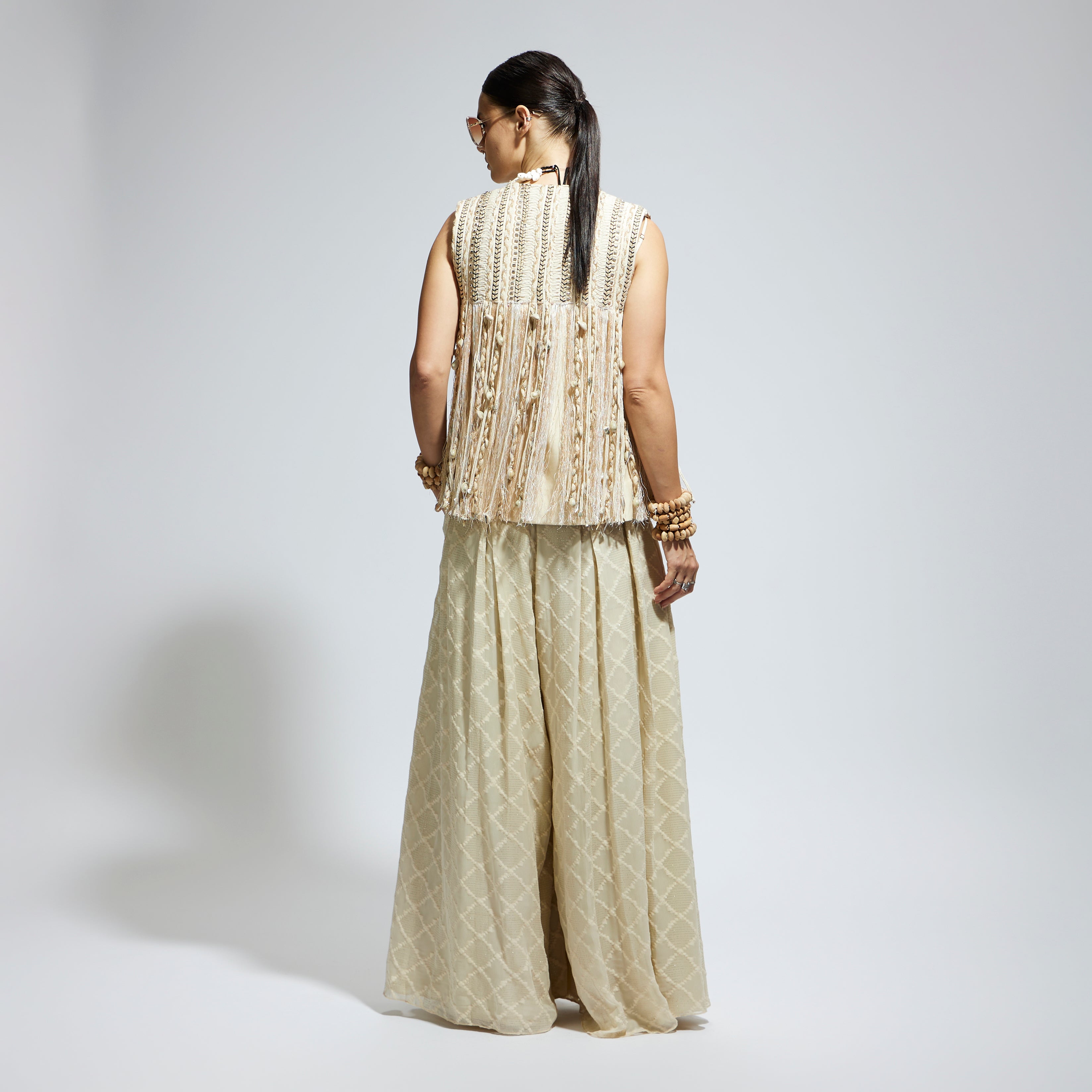 SAMSARA: IVORY THREADWORK FRINGE JACKET PAIRED WTH SCALLOP METALLIC BUSTIER AND IVORY AZTEC FLARED PANTS