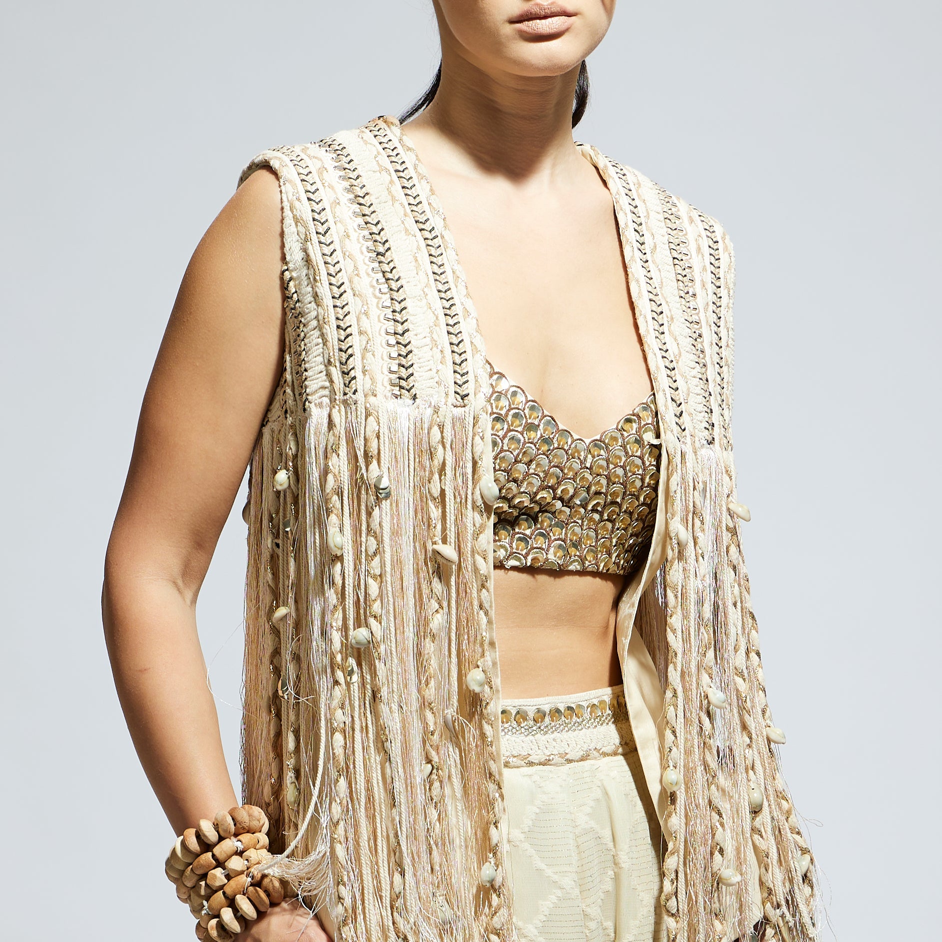 SAMSARA: IVORY THREADWORK FRINGE JACKET PAIRED WTH SCALLOP METALLIC BUSTIER AND IVORY AZTEC FLARED PANTS